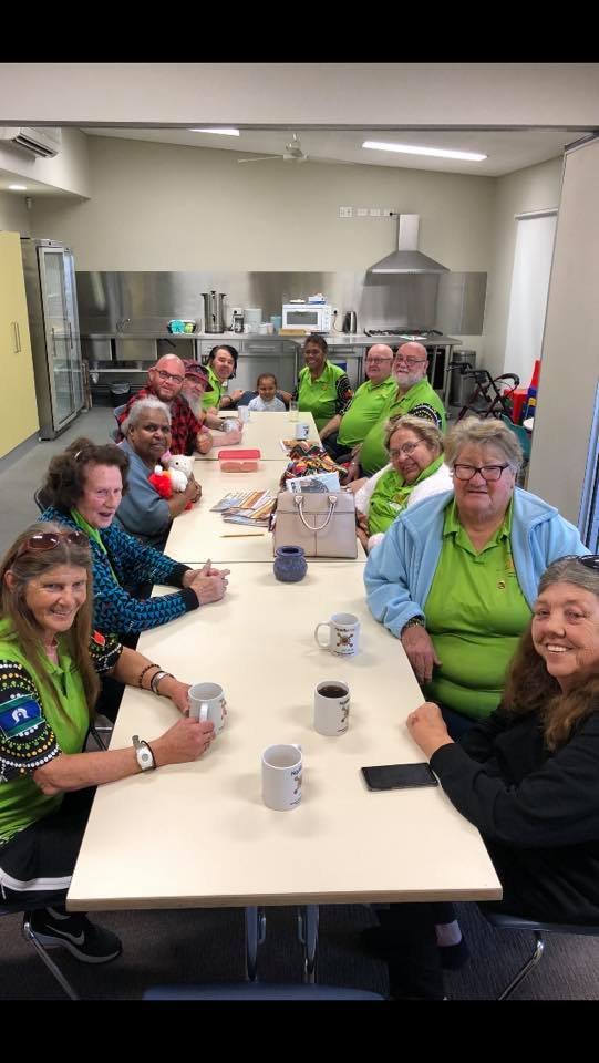 Wolkara members gathered around a long table indoors, sharing tea and coffee together.
